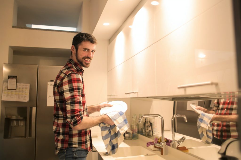 man washing the dishes near the kitchen sink